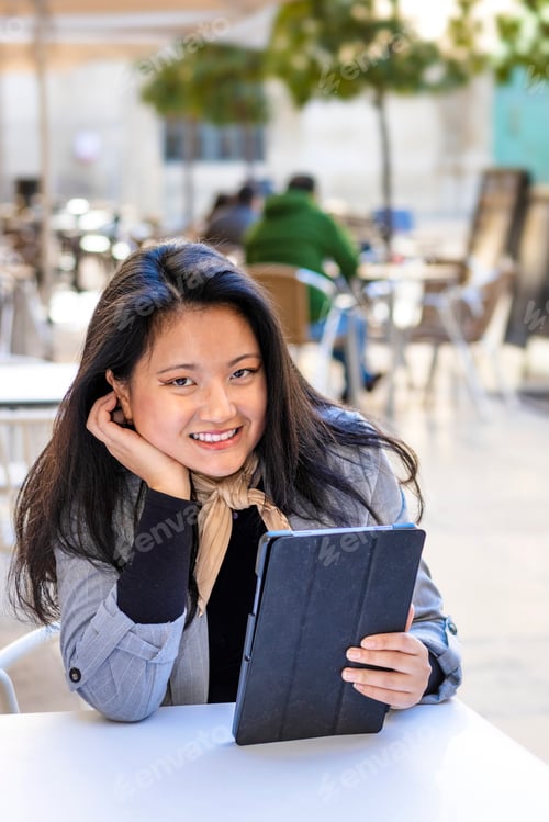 Preview: Smile happy Asian business woman wearing suit holding digital tablet siting in the street