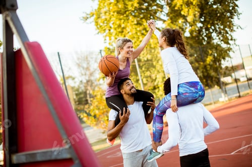 Preview: Group of multiethnic people playing basketball on court