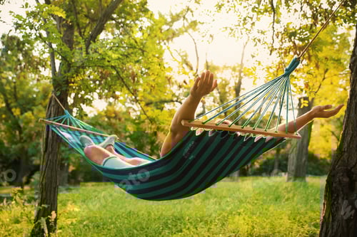 Preview: Young man resting in comfortable hammock at green garden