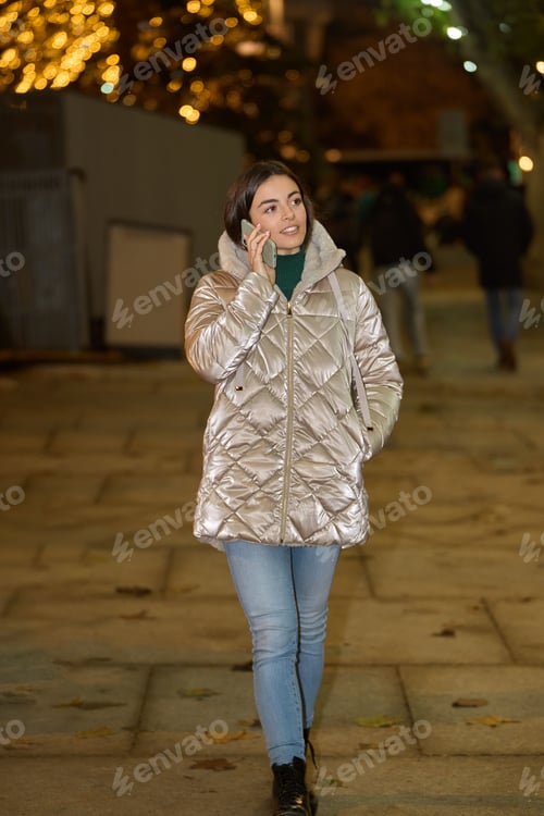Preview: Woman in winter jacket talking on the phone outdoors.
