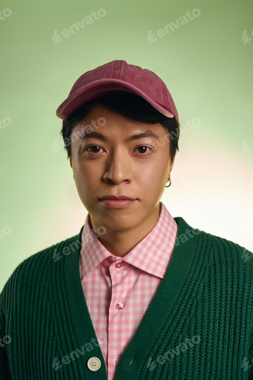 Preview: Stylish Asian man in a pink checkered shirt and green cardigan poses in a studio