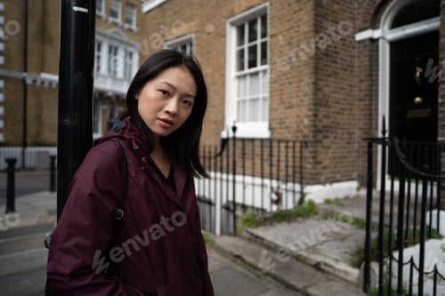 Preview: Asian woman standing near brick houses