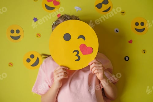Preview: The child holds smiley face that sends an air kiss.