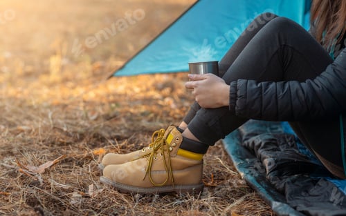 Preview: Legs in boots of woman camping in forest