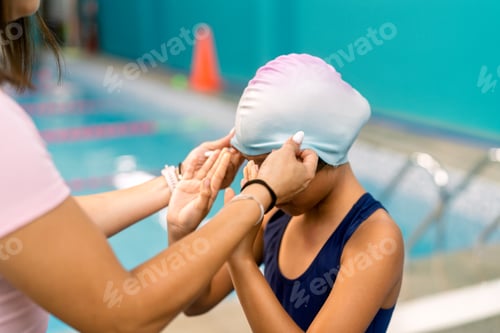 Preview: Instructor helping girl wearing swim cap for lessons