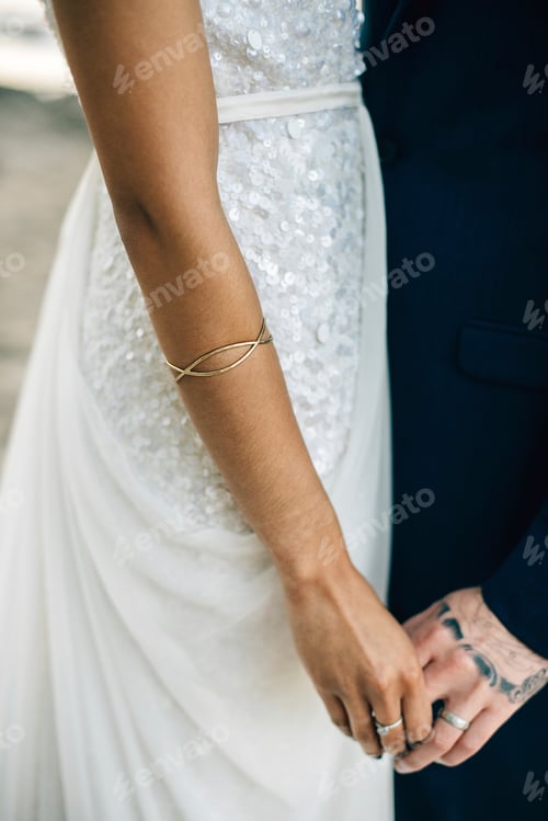 Preview: Bride and groom holding hands on lakeside, cropped