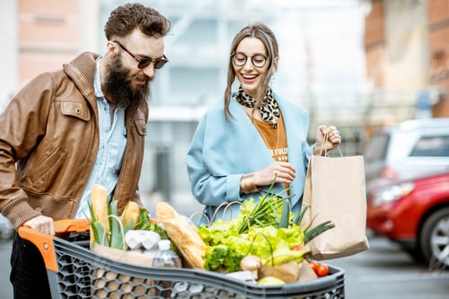 Preview: Man and woman with shopping cart full of food outdooors
