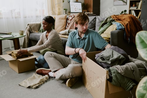 Preview: Multiethnic Adult Couple Packing Clothes for Home Donation Drive