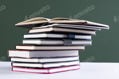 Preview: Close up of stack of books and notebooks with copy space on green background