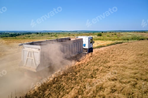 Preview: Aerial view of cargo truck driving on dirt road between agricultural wheat fields