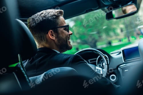 Preview: Businessman in car. Rear view of young handsome man in sunglasses looking on the right