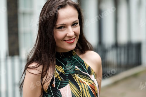 Preview: Head shot of a young caucasian woman wearing a spring dress. She is smiling and looking at camera.