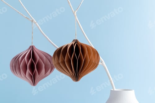 Preview: Christmas handcrafted craft paper honeycomb ornaments on white branch on blue background. Xmas greet