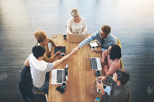 Preview: High angle shot of businesspeople shaking hands during a meeting in an office