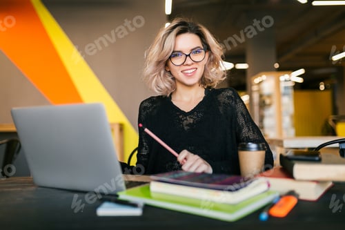 Preview: young woman working on laptop in co-working office