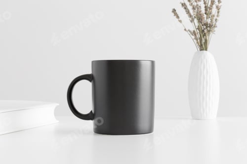 Preview: Black mug mockup with a lavender in a vase and a book on a white table.