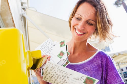 Preview: Smiling woman mailing postcards