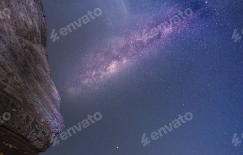 Preview: The Milky Way shining high in the night sky. A rock face in the foreground