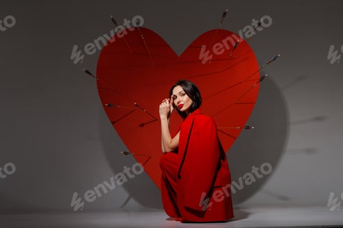 Preview: Valentines Day love concept woman in red suit by heart pierced with arrows