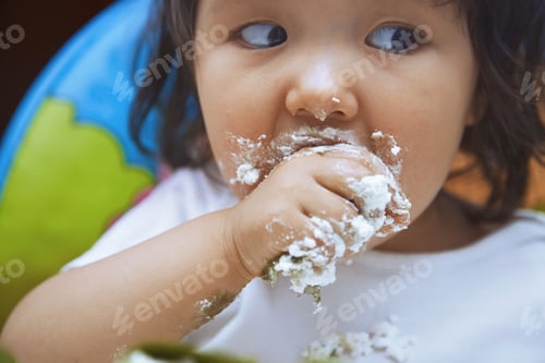 Preview: Baby with dirty face and hand eating sweet food