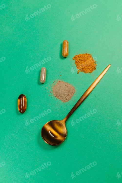 Preview: Golden spoon with pills and tablets on a green background