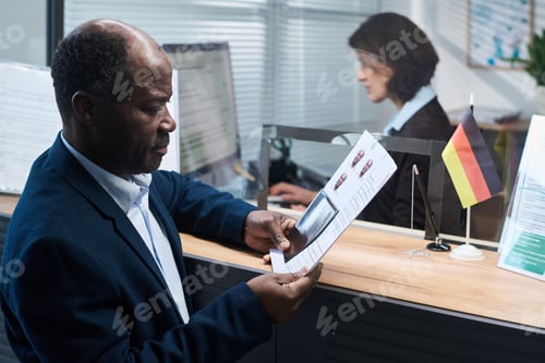 Preview: Middle Aged Black Man Reviewing Documents at Visa Center Reception Desk