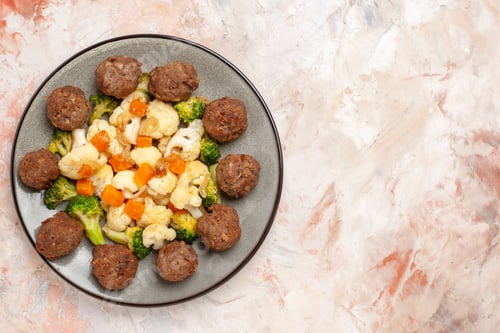Preview: top view broccoli and cauliflower salad and meatball on plate on nude isolated background with copy