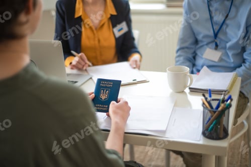 Preview: Woman and man volunteers helping Ukrainian woman to fill in forms at asylum centre.