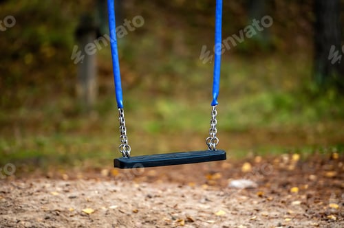 Preview: closeup of children swing seat on chains in the playground, blurred autumn background