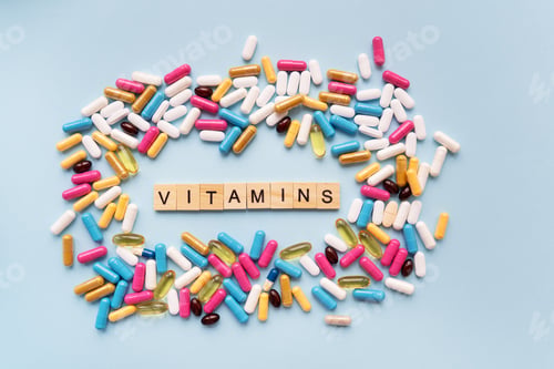 Preview: A lot of multi-colored bright tablets, in the center there is an inscription vitamins.