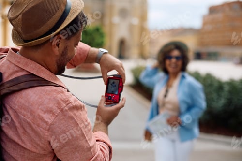 Preview: Back view of tourist photographing his wife during their travel.