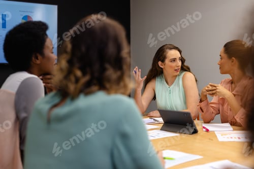 Preview: Diverse casual businesswomen in discussion using tablet in meeting room