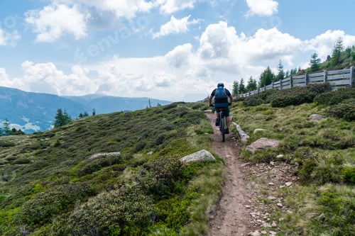 Preview: Cyclist going up a rocky mountain under a cloudy sky
