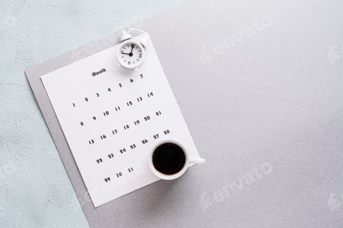 Preview: Blank sheet of monthly calendar, coffee cup and alarm clock on textured background.