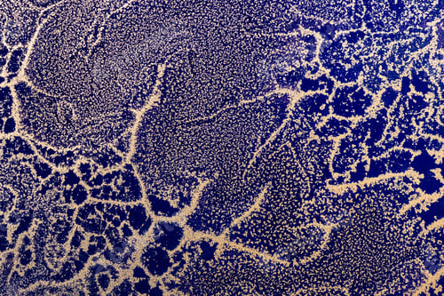 Preview: Acrylic Fluid Art. Abstract waves of gold grains pattern on dark blue background. Abstract texture