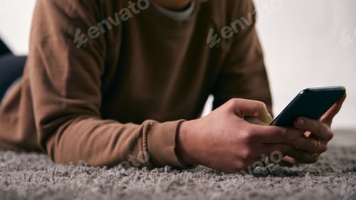 Preview: Close Up Of Woman At Home Looking At Social Media And Text Messages On Mobile Phone Lying On Carpet