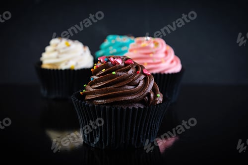 Preview: Tasty colorful cupcakes isolated on dark background. Delicious cupcake