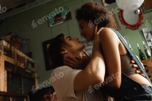 Preview: passionate multiethnic couple embracing and looking at each other in art workshop