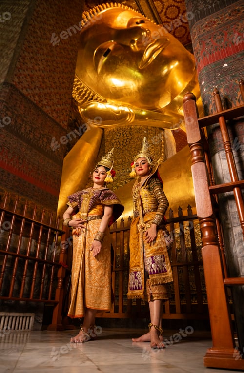 Preview: Thai dancers standing gracefully inside a temple with a large golden reclining Buddha statue