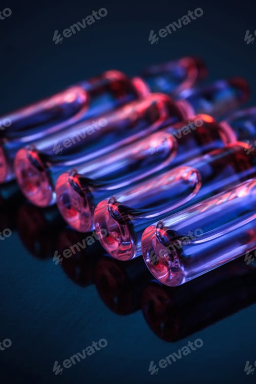 Preview: close up of row of transparent glass ampoules with liquid on table
