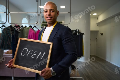 Preview: Smiling tailor inviting clients to his sewing workshop