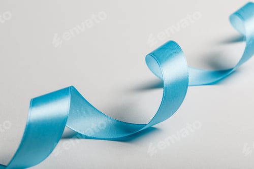 Preview: close up of curved blue satin ribbon on grey background