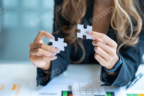 Preview: Close-up of businesswoman holding two puzzle pieces.