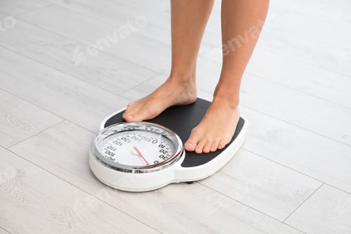 Preview: Woman standing on scales indoors. Overweight problem