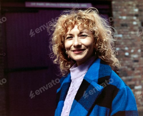 Preview: Classic portrait of smiling woman looking at camera outdoors.