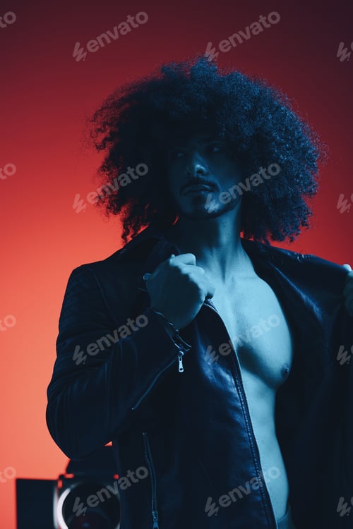 Preview: Portrait of fashion man with curly hair on red background multinational, colored light, black