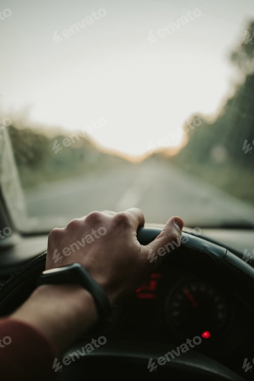 Preview: Vertical closeup shot of a hand on a steering wheel while driving