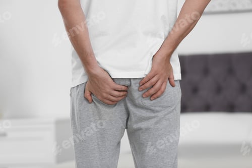 Preview: Man suffering from hemorrhoid in bedroom, closeup