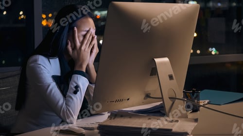 Preview: Stressed young Asian businesswoman working overtime at the office.