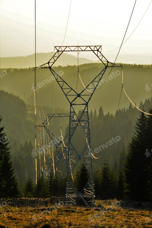 Preview: Vertical of an electricity pylon on the field against the mountains covered in greens